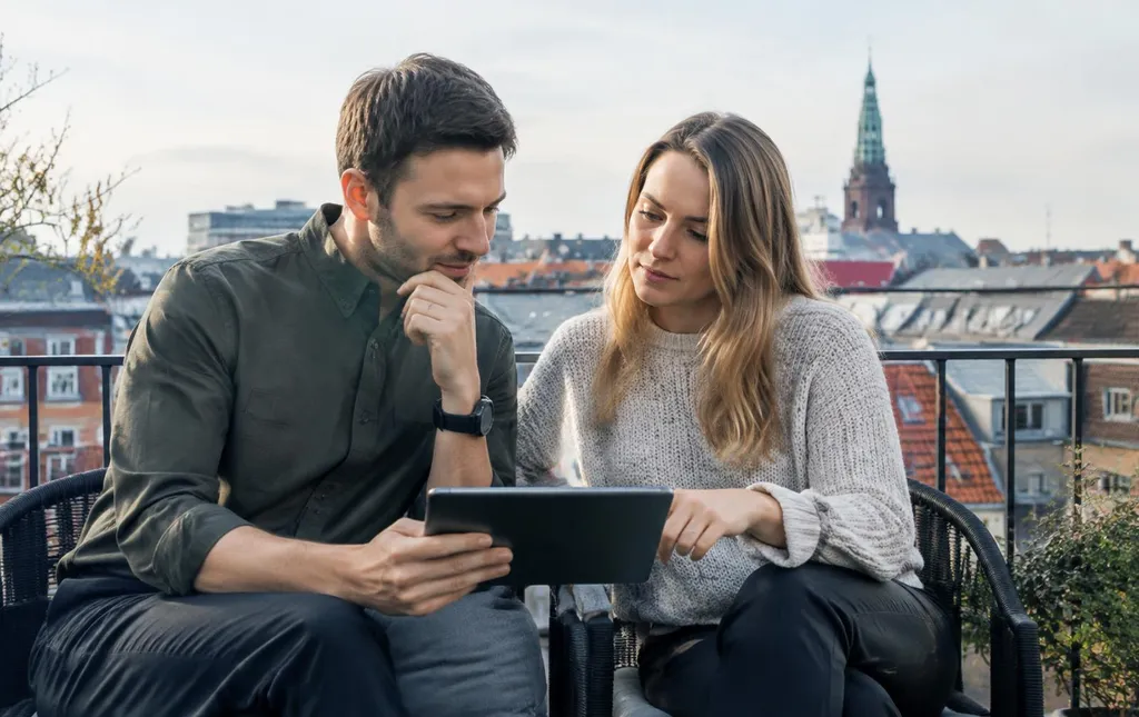 Ungt par på en altan diskuterer økonomi med en tablet